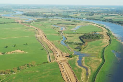 An aerial view shows the dyke construction in the middle of a river landscape.