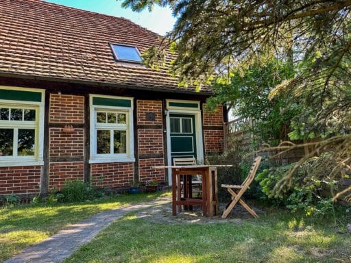 The old school is a half-timbered house with a garden. There is a seating area in front of it.