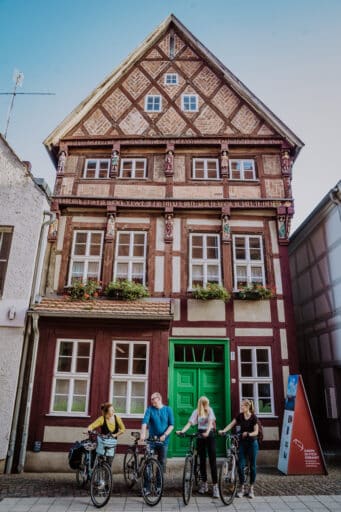 Cyclists stand in front of a half-timbered house.