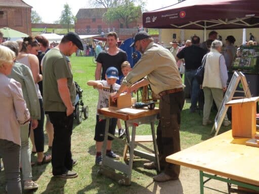 A ranger builds a bird house with children at the Biosphere Elbe Market at Dömitz Fortress.