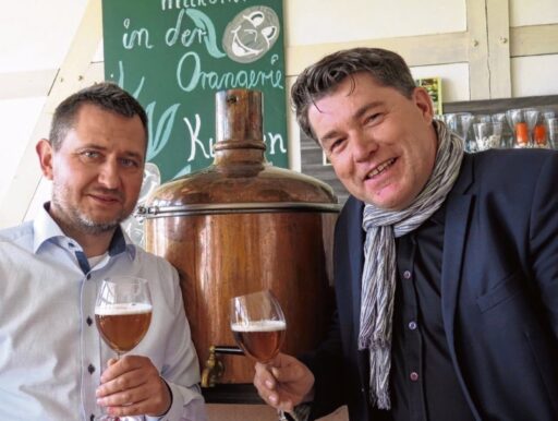 The bosses of the brewery in front of the brewing kettle with a glass of beer in their hands