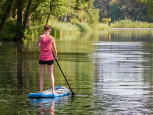 a young woman stand-up paddling on the canal