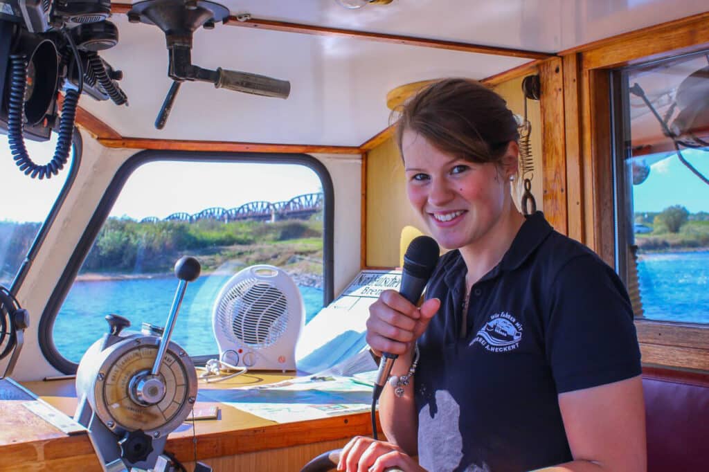 Zertifizierte Natur- und Landschaftsführerin Carina Heckert auf dem Schiff MS Hecht mit einem Mikrofon in der Hand.