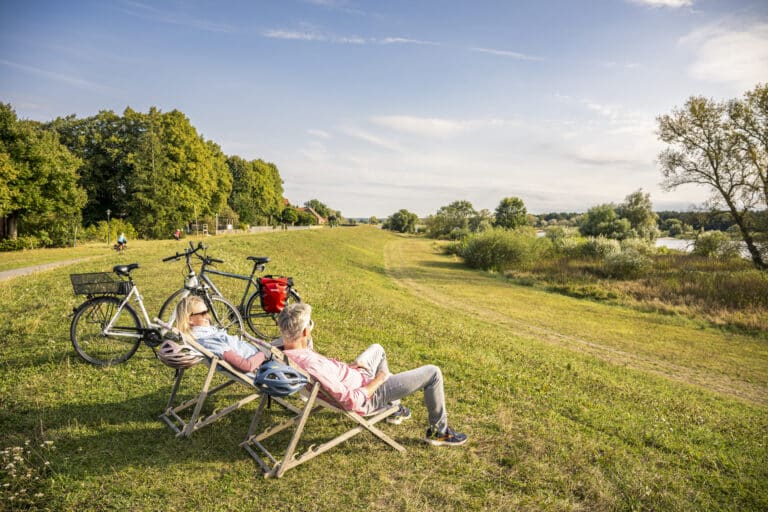 Menschen sitzen in Liegestühlen auf dem Elbdeich