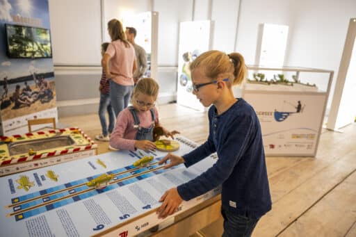 Kinder spielen an einem Modell im Bioshaerium Elbtalaue.