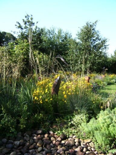 Solmmergarten with yellow flowers and decorative metal bird