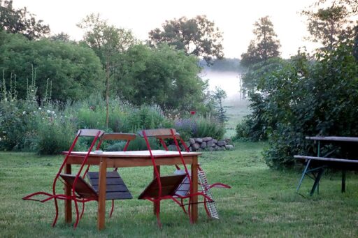 Tables and chairs stand in a foggy garden.