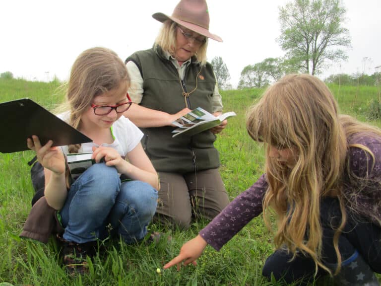 Kinder bestimmen mit Hilfer einer Rangerín Pflanzen.