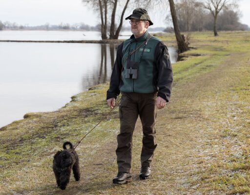 The certified nature and landscape guide Uwe Kühn goes for a walk along the Elbe with his dog Charlie, equipped with binoculars and official clothing.