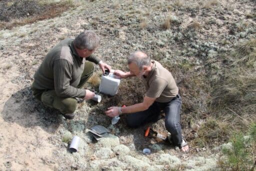 Two men prepare insect traps on a dry grassland for research purposes