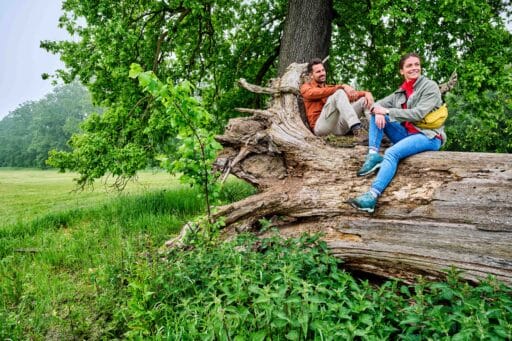 Two people take a break on a tree trunk.